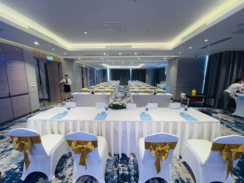 Bàn họp dài phủ khăn trắng, ghế nơ vàng trong phòng Hạ Long, tầng 3 À La Carte Hạ Long