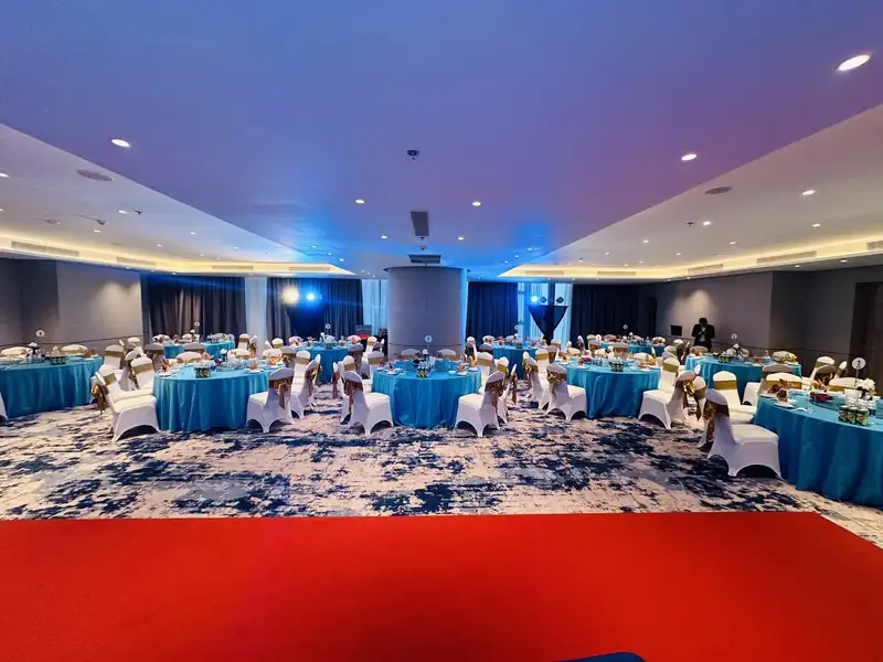Ocean Ballroom bày tiệc bàn tròn khăn xanh, thảm đỏ dẫn lên sân khấu – tầng 3 À La Carte Hạ Long