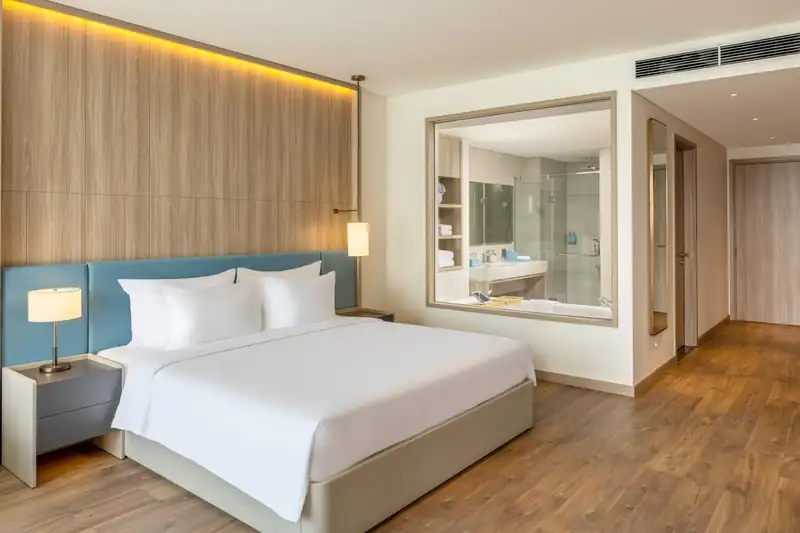 Giường đôi lớn phòng Executive Bay View, vách kính nhìn vào phòng tắm