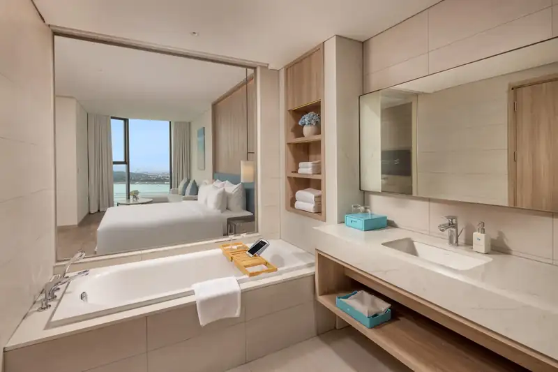 Bồn tắm cạnh vách kính, nhìn qua giường ra vịnh trong phòng Executive Bay View