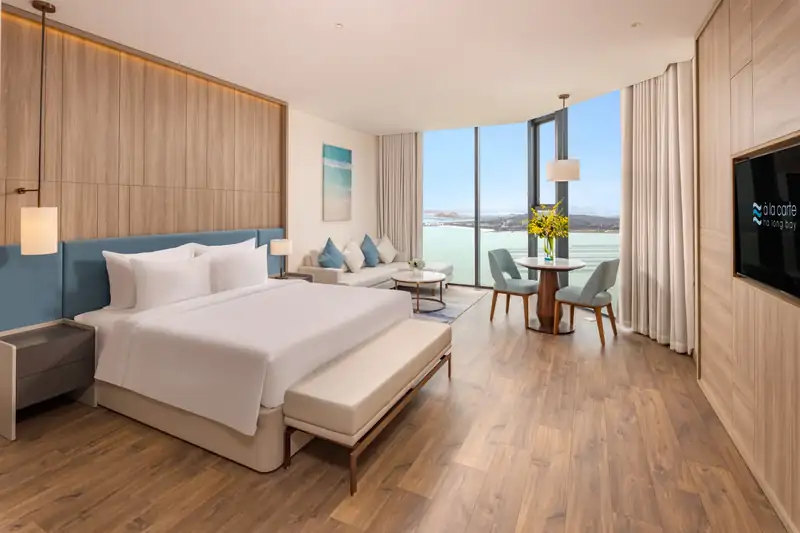 Phòng Executive Bay View: giường đôi lớn, góc tiếp khách và cửa kính nhìn ra vịnh Hạ Long