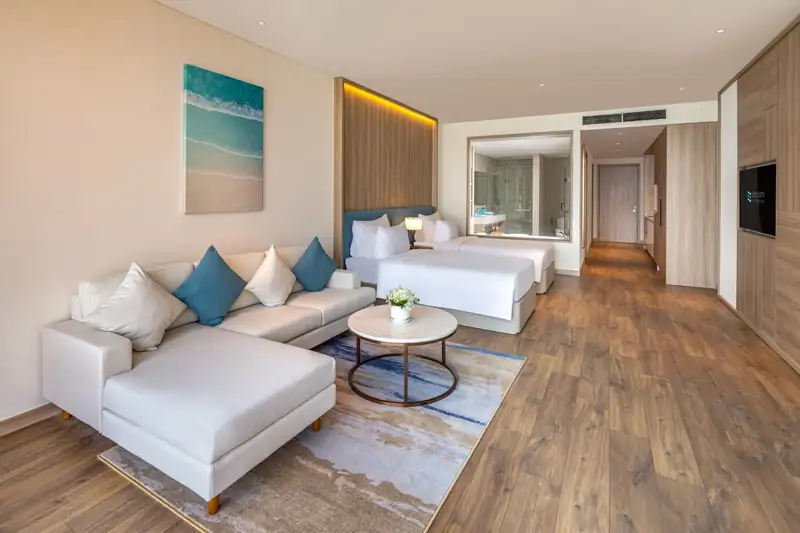 Góc sofa và bàn trà trong phòng hạng Premier, phía sau là 2 giường đơn