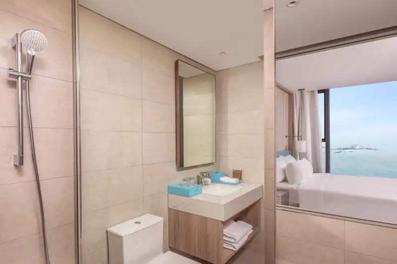 Phòng tắm vòi sen trong Suite Bay Vista, nhìn qua vách kính ra giường và vịnh